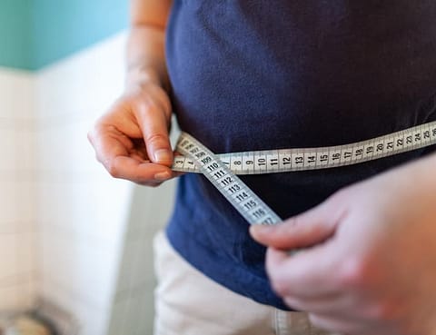 Man Measuring Waist To Monitor Weight Loss