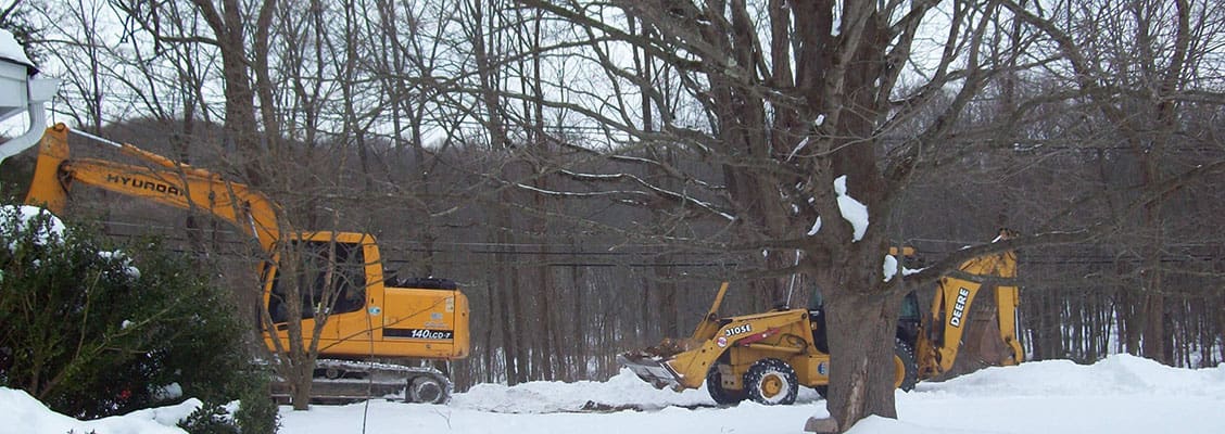 Two backhoe diggers being used in an outside area.