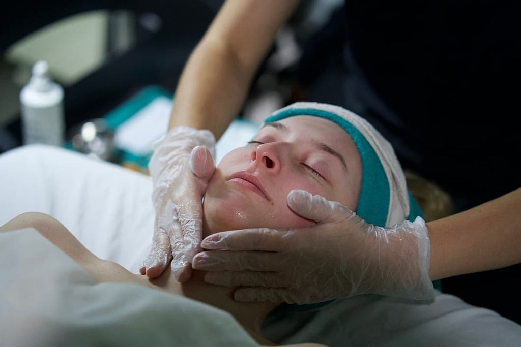 woman laying on table with eyes closed receiving cosmetology treatments