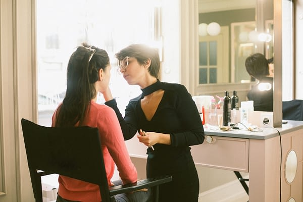 woman doing another woman's makeup in a salon