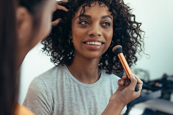 woman having her makeup done by another woman