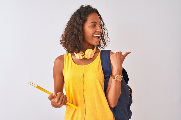 woman in yellow top wearing backpack laughing and pointing over her shoulder