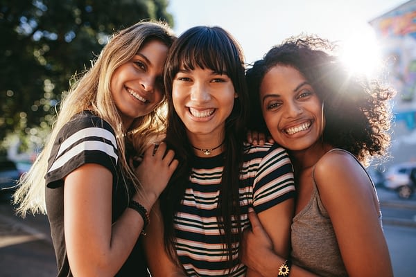 three women hugging and smiling outside