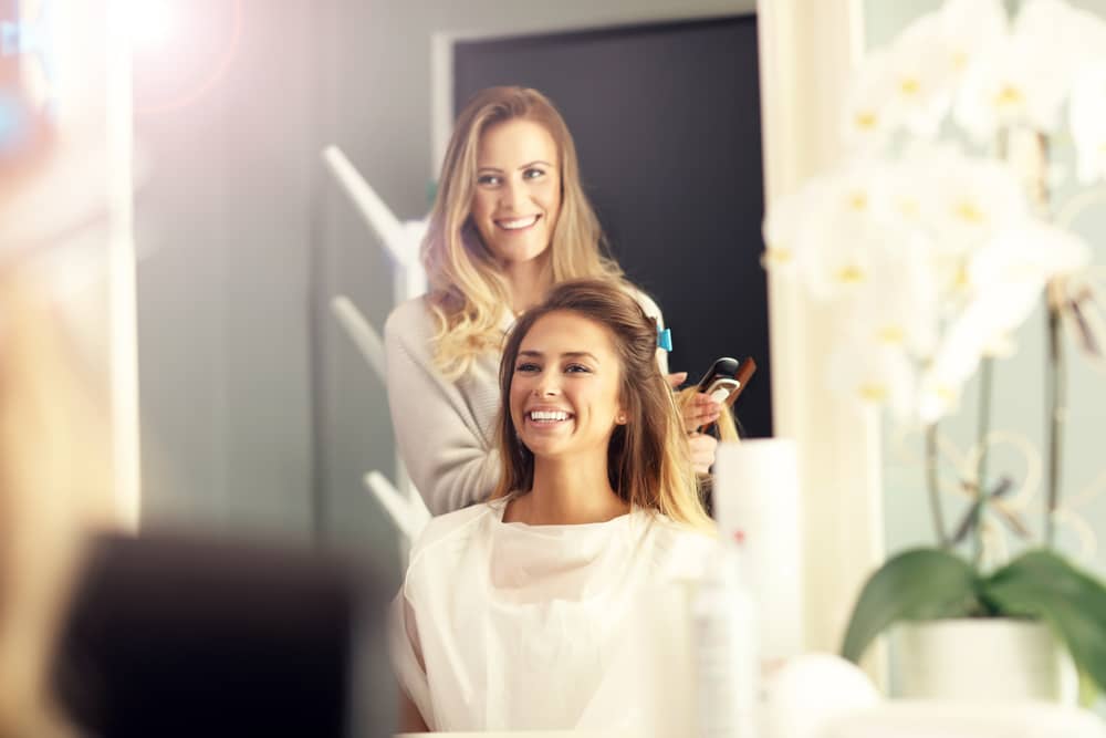 Hairstylist doing woman's hair both are smiling