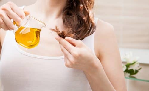 woman applying oil product to her hair