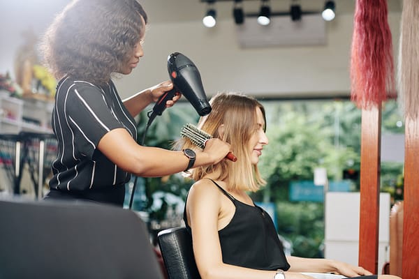 Hair stylist blow drying woman's hair