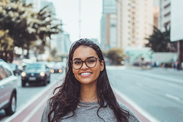woman wearing glasses standing in a street downtown