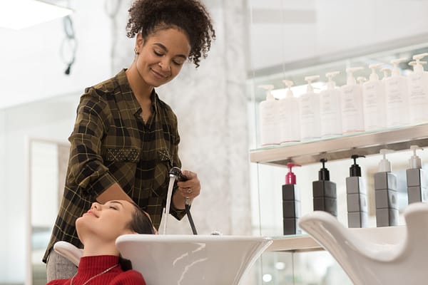 Young lady washing woman's hair in a hair salon
