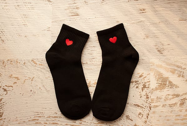 black socks with red hearts laid out on a wood table
