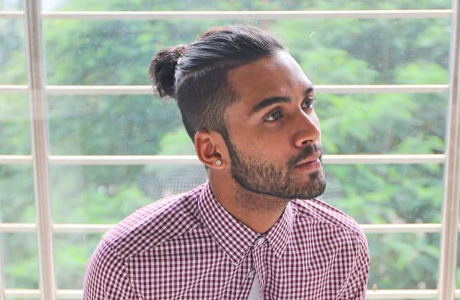 Model with manbun sitting looking to the right