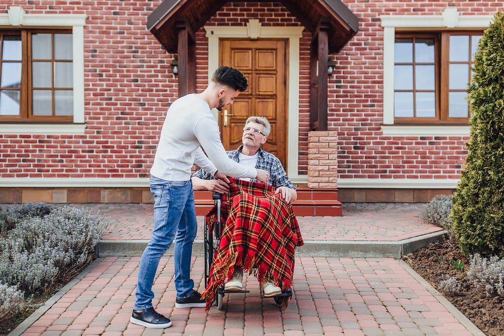 Son helping senior father in wheelchair