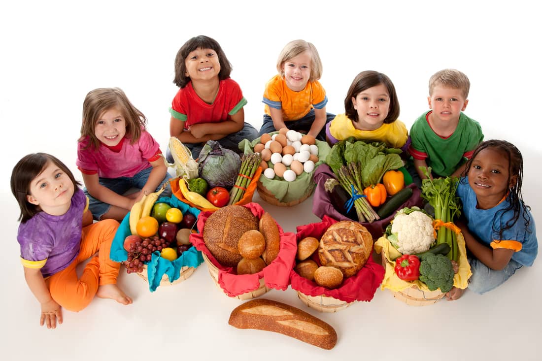 Kids sitting around a group of healthy foods