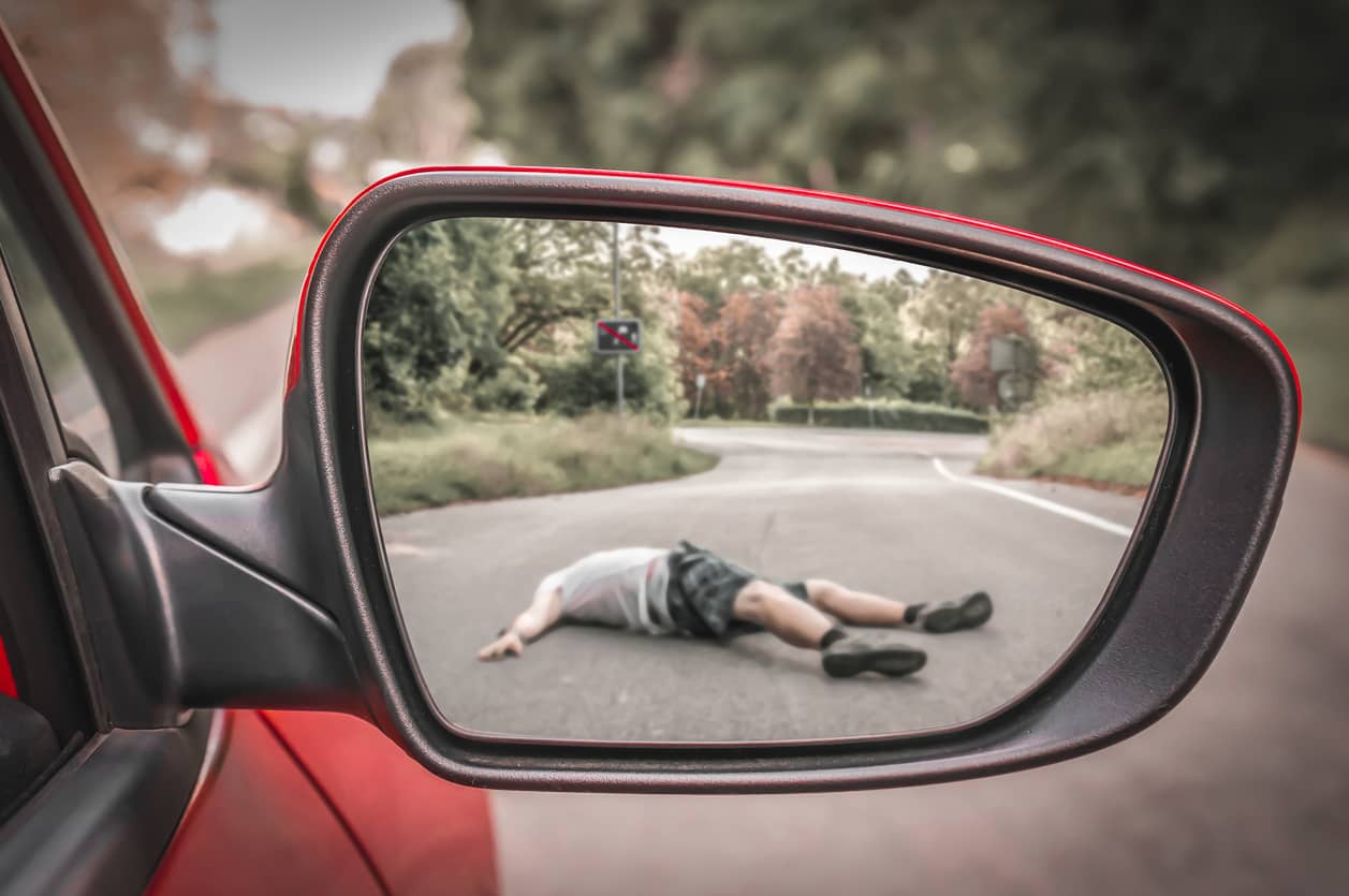 a man lying on the ground reflected in a rearview mirror