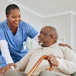 Caregiver assisting a patient get up from seated position