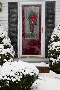 Red front door with glass storm door during snowstorm