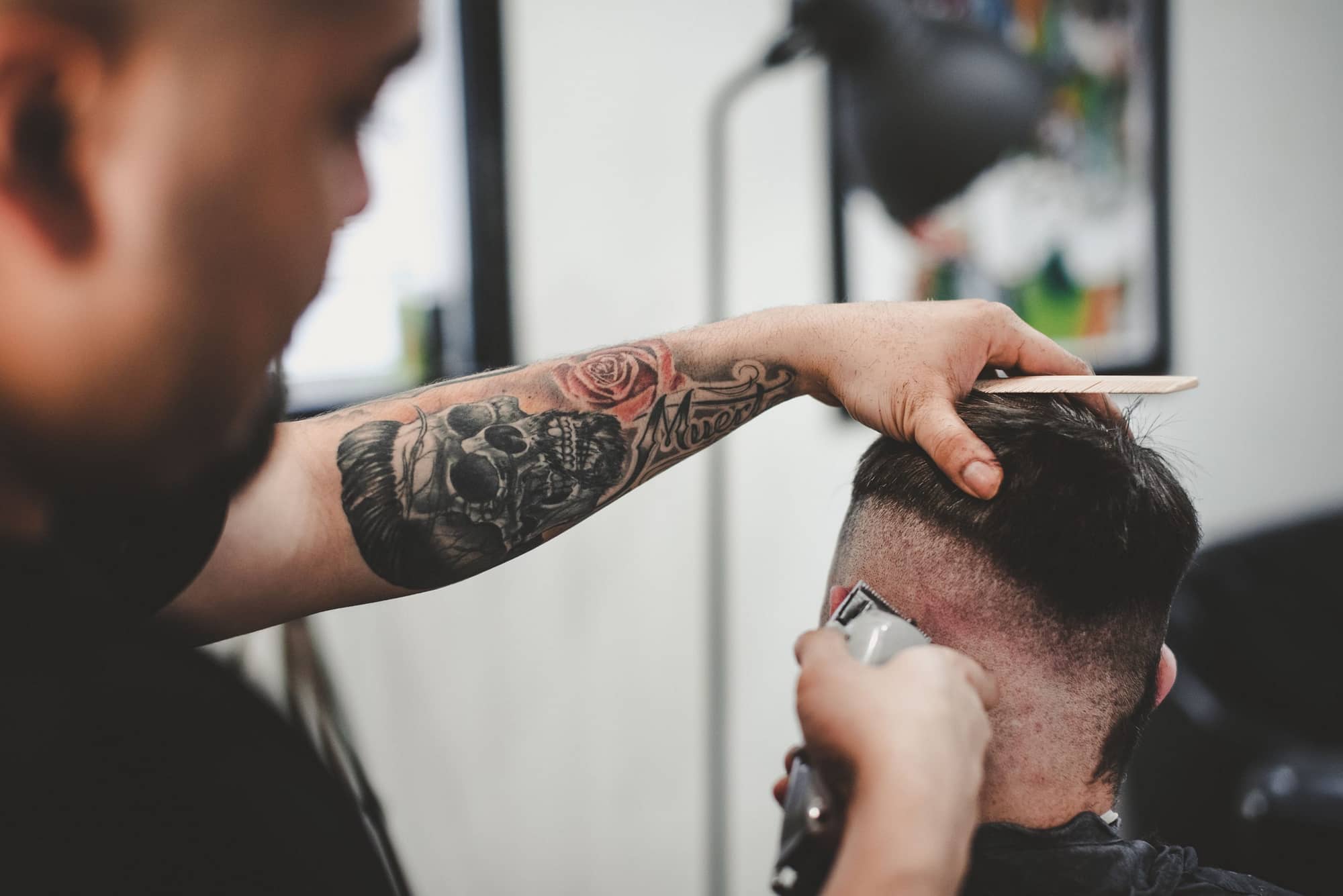 barber with tattoo cutting hair