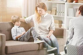 Mother and son sat on couch talking to doctor