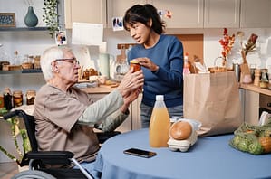 Caregiver unpacking groceries for a client in their kitchen