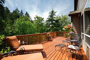 A sunny back deck with trees and outdoor furniture