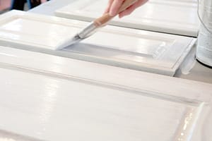Closeup of person painting kitchen cabinets white