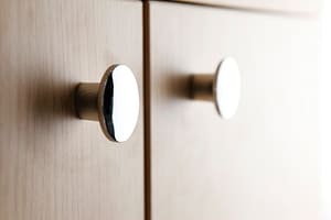 Closeup of round silver pulls on brown cabinets
