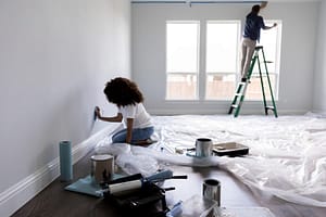 Couple applying painter’s tape to room to prepare for painting