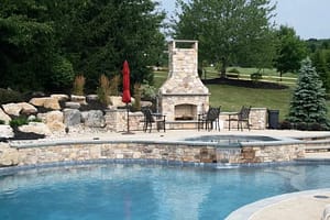 Stone fireplace overlooking stone-lined pool 