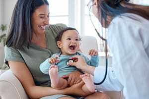 Mother holding baby while pediatrician examines with stethoscope 