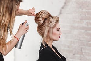 hairdresser styles a blonde woman's hair