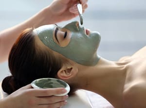 female spa client has mud face mask applied to her face