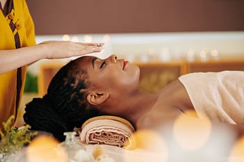 Reiki client lying down with eyes closed and practitioner's hand over head