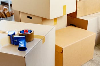 Group of cardboard moving boxes with a packing tape dispenser