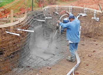 Construction worker spraying gunite to build swimming pool