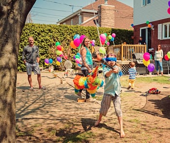 A blindfolded guest at a backyard party hits a pinata 