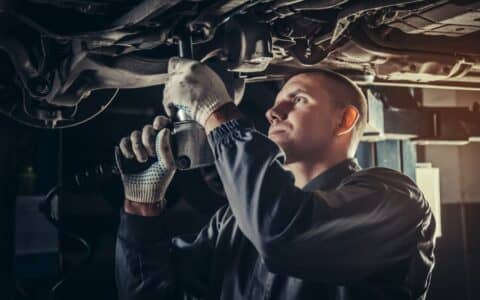 Mechanic performing repair services beneath vehicle