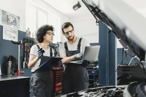 Auto mechanics use a laptop to diagnose issues with a vehicle
