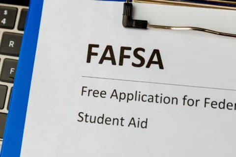 A clipboard resting on a laptop keyboard with a FAFSA application form