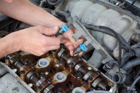 Car mechanic fixing a direct-injection engine