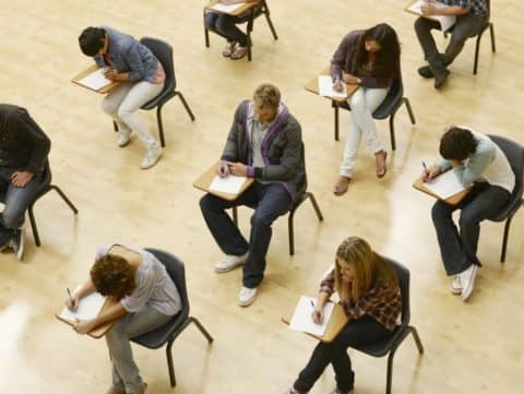 College students spaced apart in desks taking tests in classroom