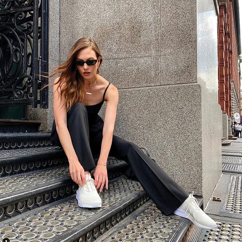 Karlie Kloss, sitting on stairs with wind blowing her brown highlighted hair