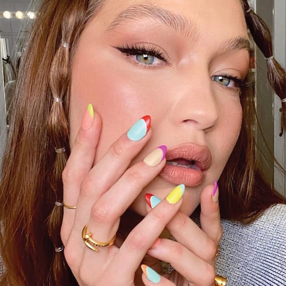 french tips trend, Gigi Hadid holding hand to face with brightly colored nails
