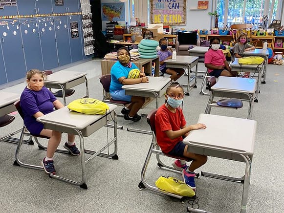 Young students sat in classroom wearing face masks for covid