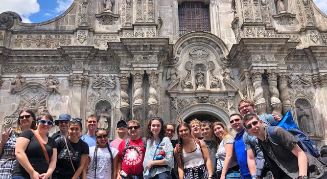 High school travel group posed in front of historic cathedral
