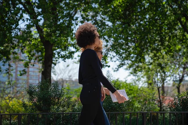 two African American women walk side by side in a park