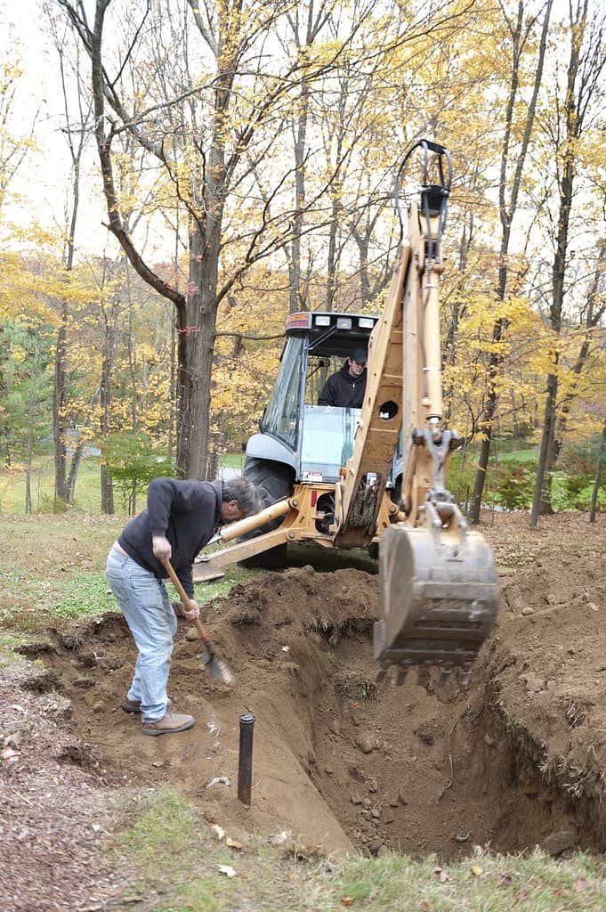 Two men working to remove an old oil tank from a hole in the ground