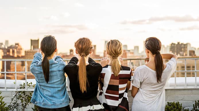 A line of women standing against a city sky line