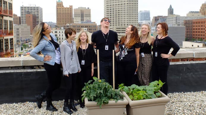 A group of Aveda students, in New York laughing at some garden boxes on a roof.