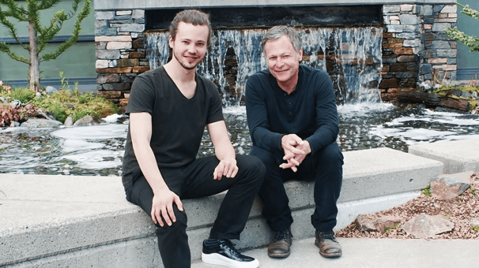 Two men sitting in front of a water fall