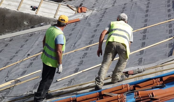 A crew works on a roof for a commercial building