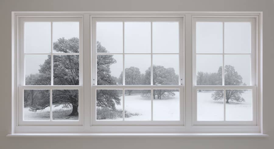 three white windows looking out over a snowy field with trees